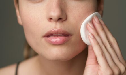 Young woman using a cotton pad for skincare, highlighting beauty routine.