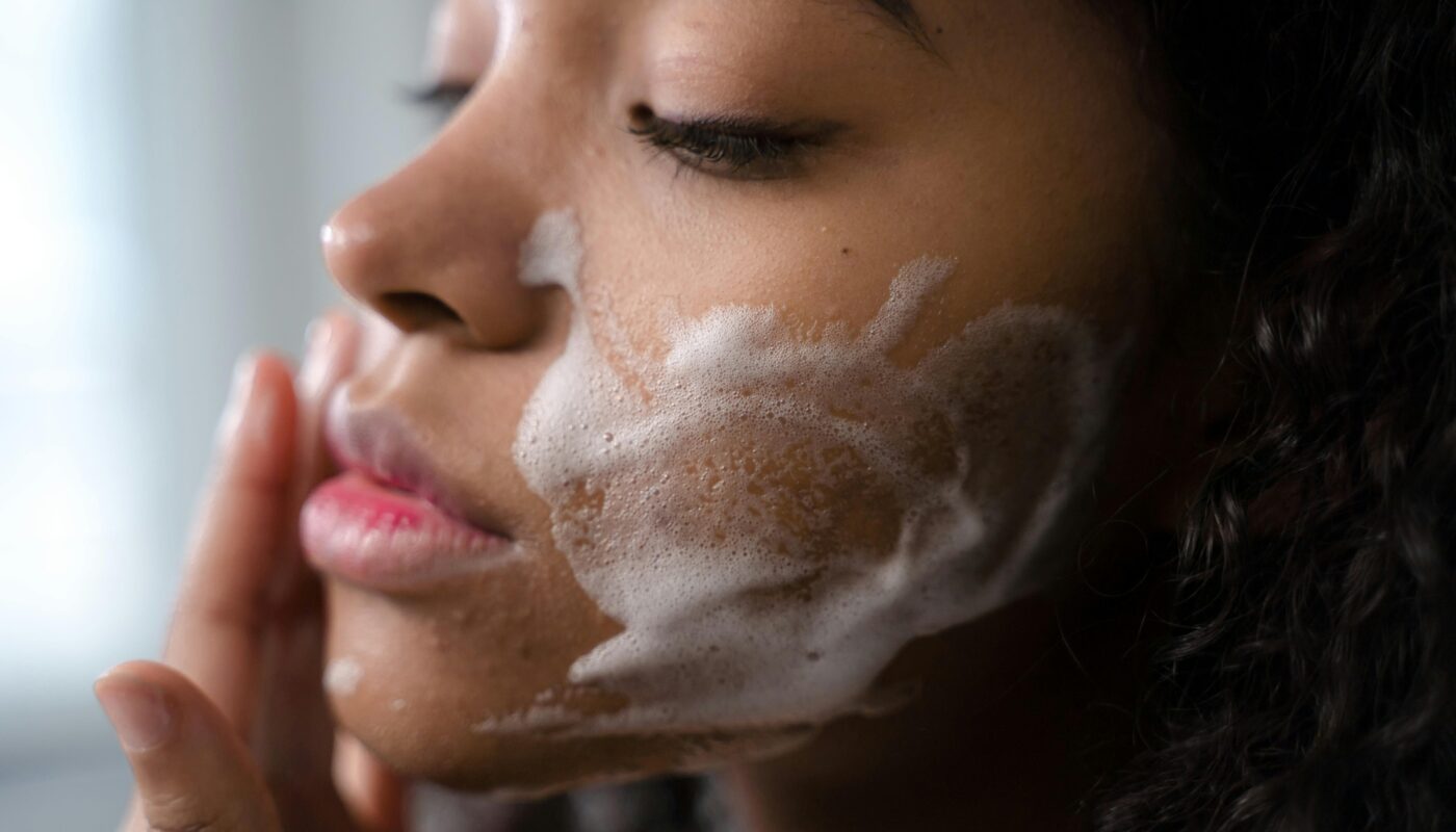 A woman applies skincare foam to her face for a gentle cleansing routine.